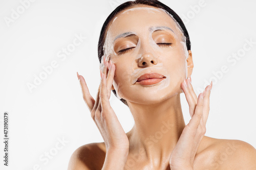 beautiful woman in a moisturizing facial mask, skin care. Woman applying a cosmetic tissue mask to her face photo