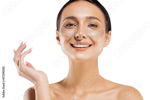 tender woman standing naked, with collagen blindfolds on her eyes, taking care of her skin with spots under the eyes photo