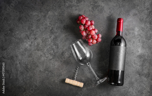 Red wine in bottle and grape on dark stone background. Copy space