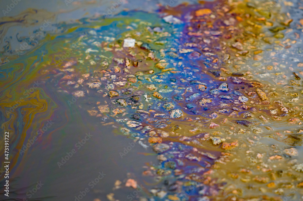 Fuel stain on wet asphalt. Colored stains from a gasoline leak on the road. Fuel stain on wet asphalt. Colored stains from a gasoline leak on the road.
