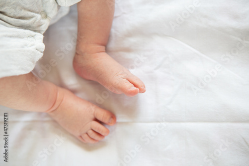 Small feet of a newborn baby on the bed, top view. The concept of motherhood, breastfeeding.