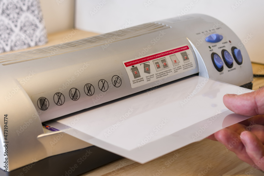 Mature Man using thermal plasticizing machine, laminate signs to the office Mature Man using thermal plasticizing machine, laminate signs to the office