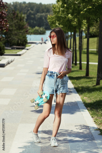 skater woman in sunglasses with blue skateboard outdoors