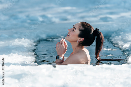 Schilderij op canvas Girl with bikini and a watch in frozen lake ice hole