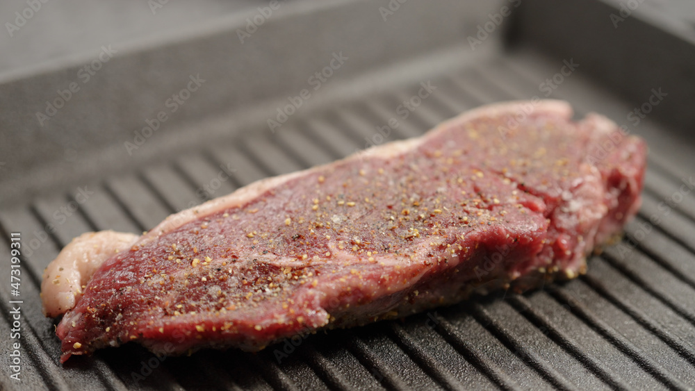 frying new york steak with tongs on grill pan