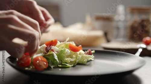 Wallpaper Mural man hand put cherry tomatoes over mixed greens on black plate closeup Torontodigital.ca