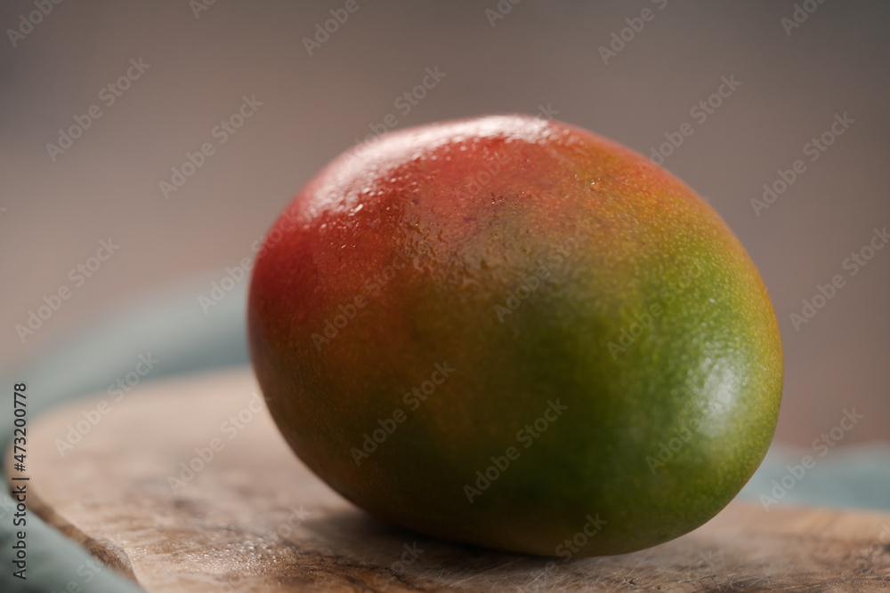 Whole ripe red mango on olive wood board Whole ripe red mango on olive wood board