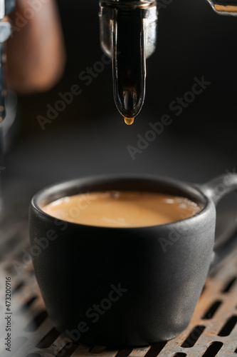 Closeup espresso last drop with single spout portafilter in black cup