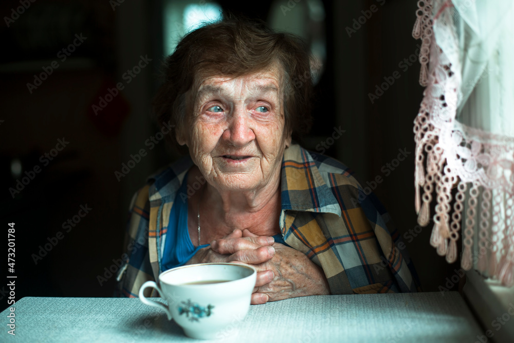 The look and smile of an elderly woman against a dark background near a window. The look and smile of an elderly woman against a dark background near a window.