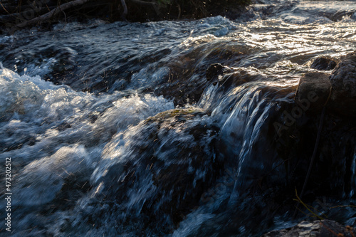 Water rolls down stone rapids in the sun