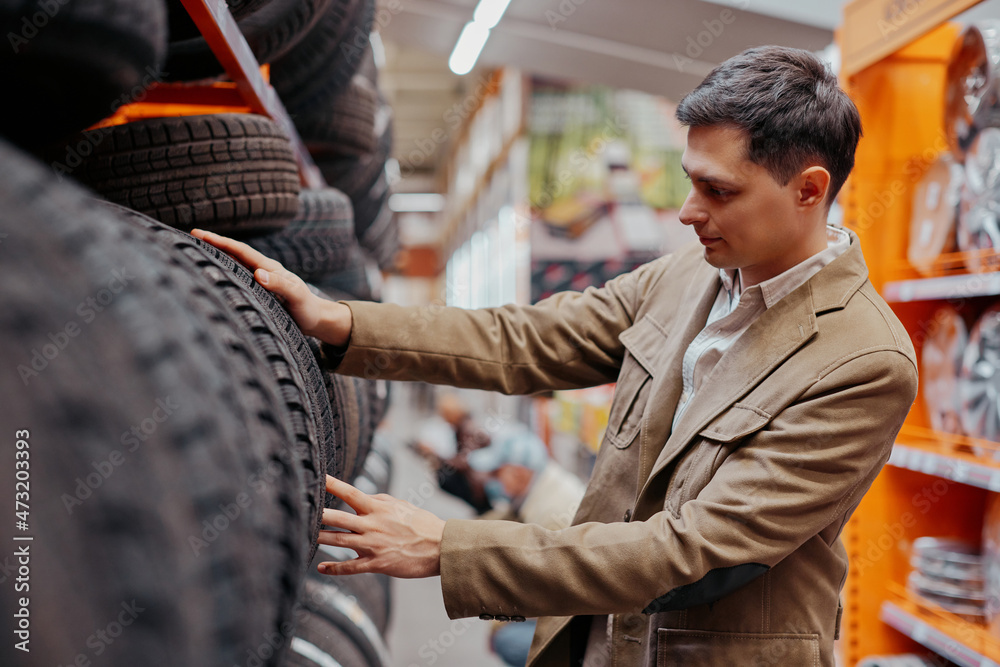 male customer choosing new tires in the supermarket . male customer choosing new tires in the supermarket .