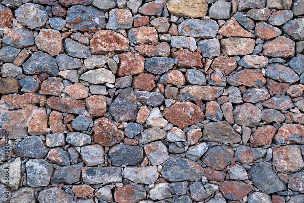 Textured background of masonry walls made of natural multicolored stones.