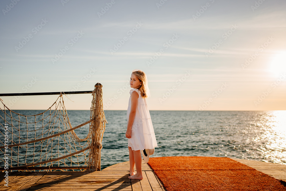 a little girl in a white dress by the sea on the pier