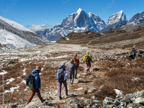 group of tourists in sun shining day going by valley to mountains peaks in Nepal