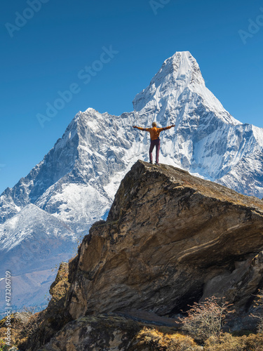 A woman tourist posing with hands up and looking to peak Ama Dablam in Nepal