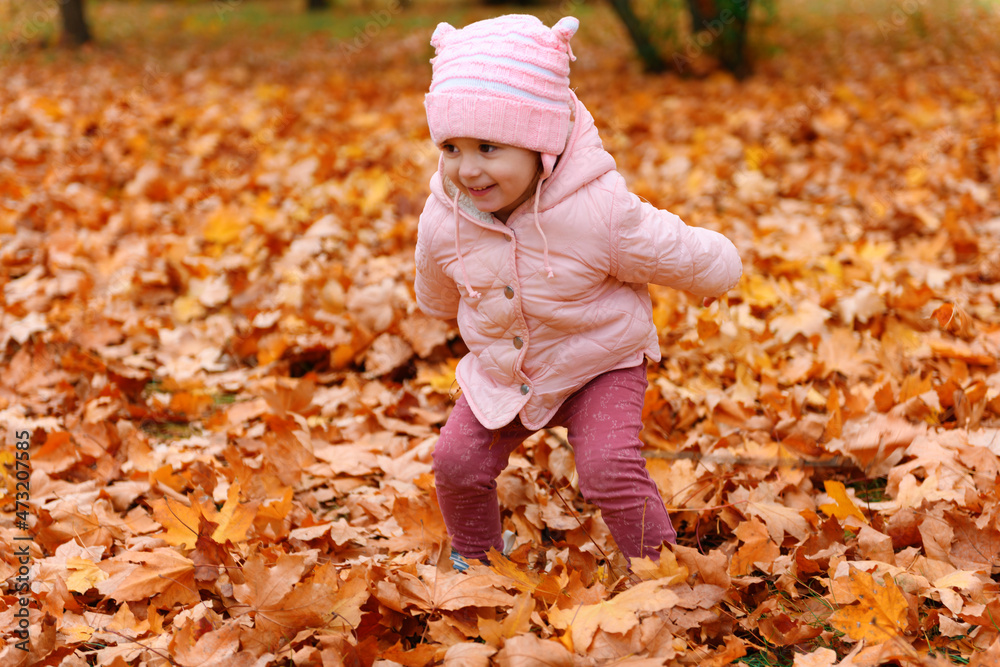 Child girl playing with fallen leaves in autumn city park. Beautiful nature, trees with yellow leaves. Child girl playing with fallen leaves in autumn city park. Beautiful nature, trees with yellow leaves.