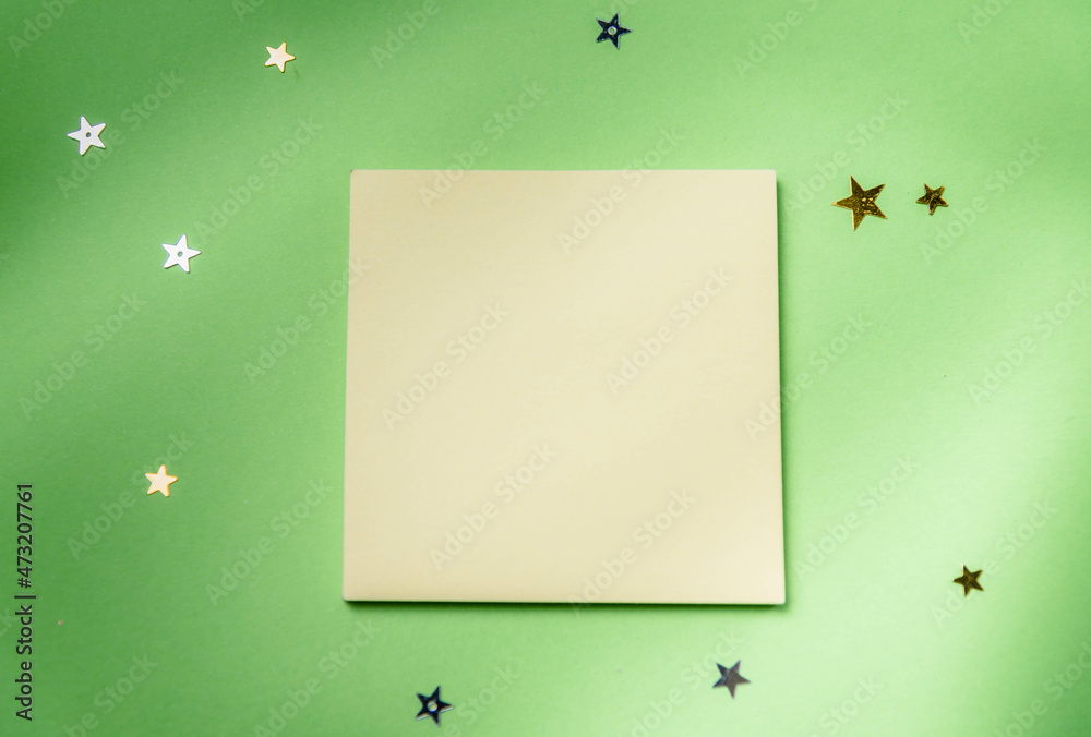 Yellow memo stick on green background with stars