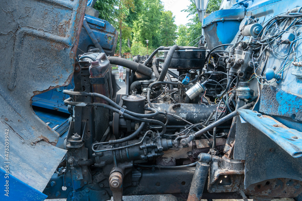 An old broken-down truck with an open hood. Car engine parts close-up. Repair of the engine of a very old car on the street. Problems with the car motor after the accident. An old broken-down truck with an open hood. Car engine parts close-up. Repair of the engine of a very old car on the street. Problems with the car motor after the accident.