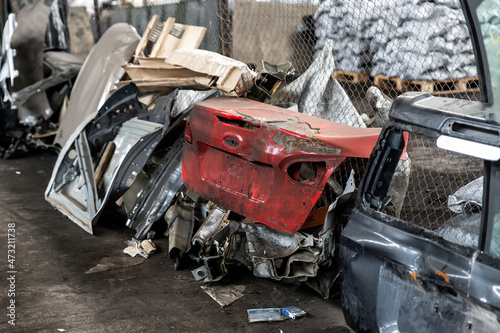 Heap of old rusty disassembled car parts at workshop waste storage hangar indoor. Vehicle salvage dismantling garage. Iron auto spare details trunk pile for recycling at scrap junkyard