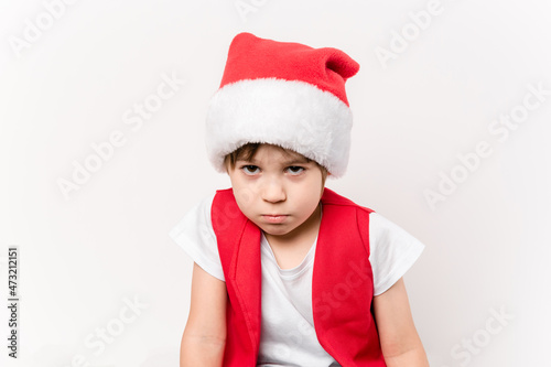 Portrait of angry resentful little child in red Santa Claus hat isolated on white background. Beautiful 5 year European boy. Without gifts. Copy space. Merry Christmas. Bad mood. New Year Close-up