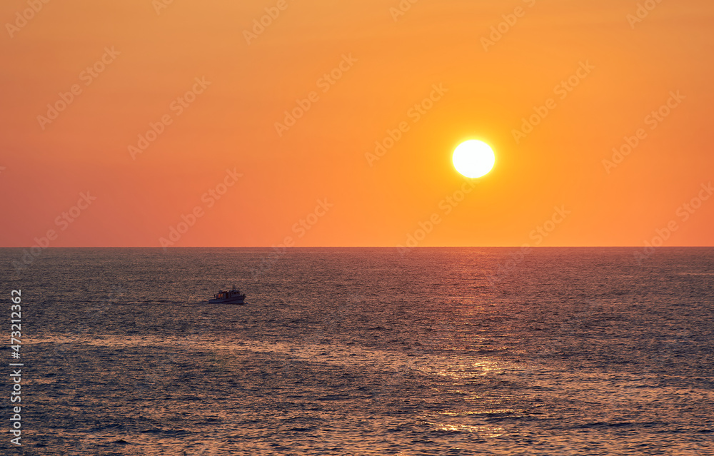 paisaje de un barco pesquero navegando bajo el sol del atardecer