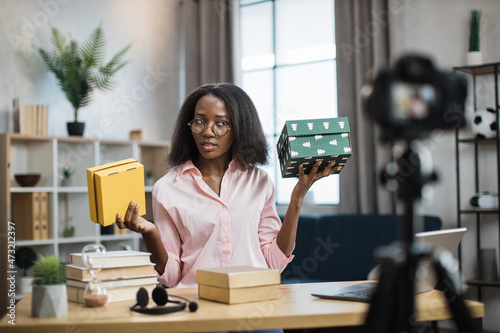 Obraz na plátně African american woman filming video on camera while unboxing presents
