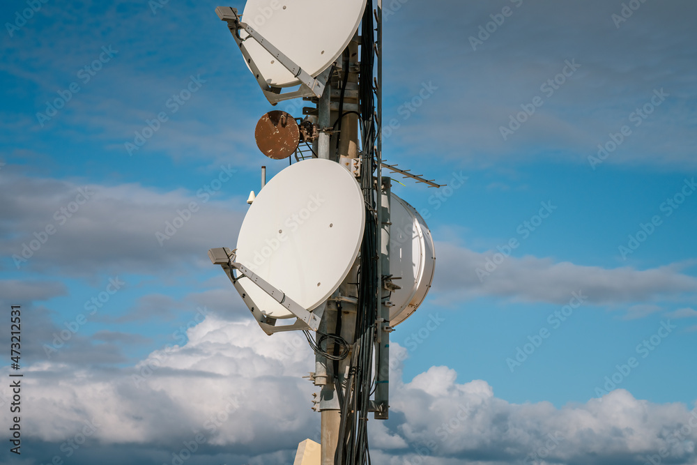 Telecommunication mast TV antennas wireless technology with blue clouds sky, city and mountains at background, close up, front view Telecommunication mast TV antennas wireless technology with blue clouds sky, city and mountains at background, close up, front view