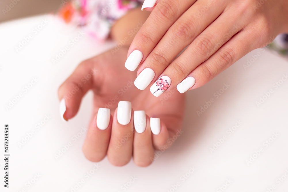 Naklejka premium Close up view of beautiful female hands with romantic manicure nails, pink and white gel polish, peonies flowers design