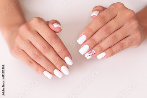 Close up view of beautiful female hands with romantic manicure nails, pink and white gel polish, peonies flowers design