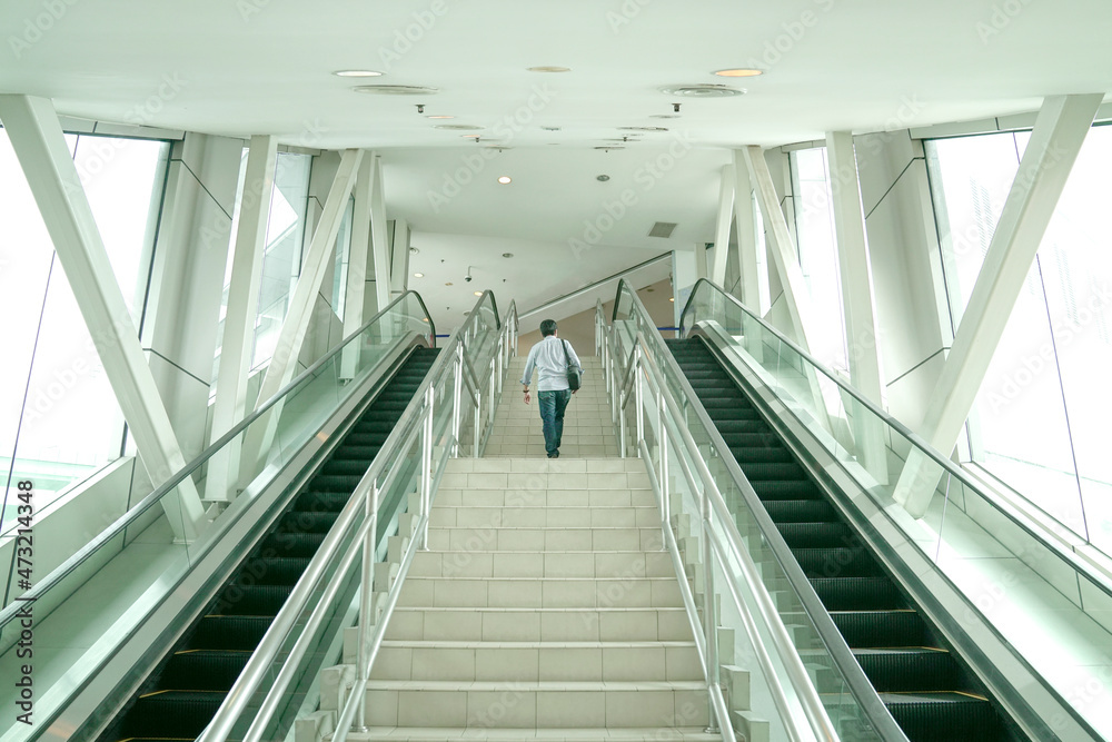 Man going up the stairs inside a modern building. Going back to work or climbing corporate ladder concept. Man going up the stairs inside a modern building. Going back to work or climbing corporate ladder concept.