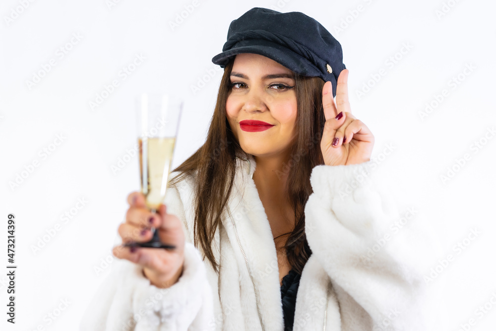 Young Latin girl with black hat celebrating New Years Eve on a white background. Portrait with a glass of champagne