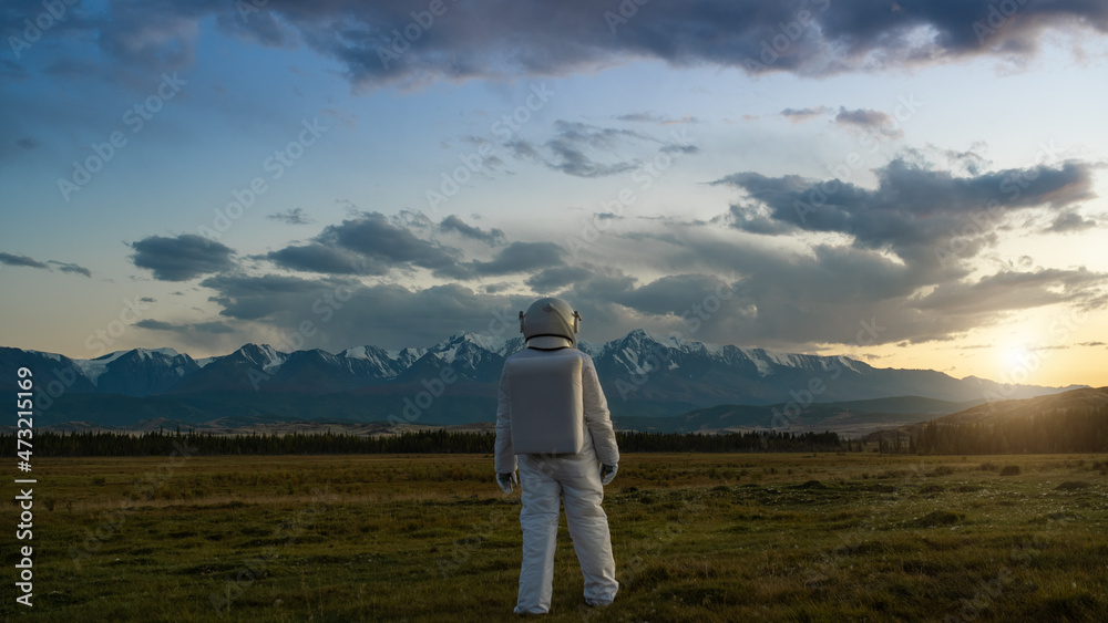 An astronaut explores an unknown planet. Sunset sky and mountains in the background.