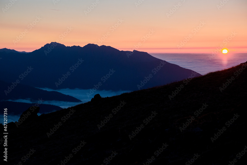 blue sunset on a mountain over a sea of clouds in the valley below