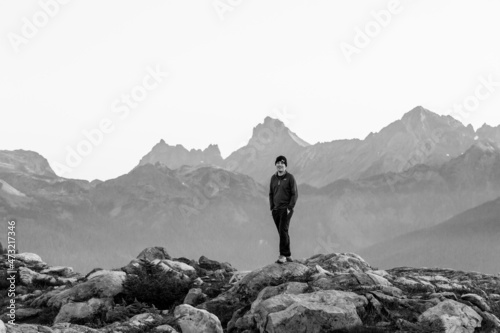 man hiking and standing in front of jagged north cascade mountain range