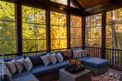 Cozy screened porch in early morning, rain drops on window and autumn leaves and woods in the background.