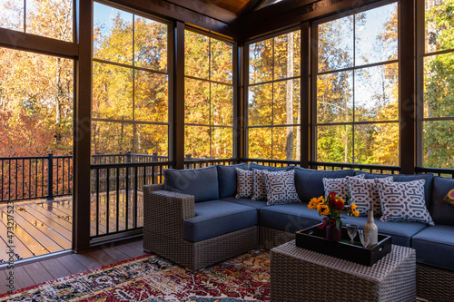 Cozy screened porch in early morning, rain drops on window and autumn leaves and woods in the background.