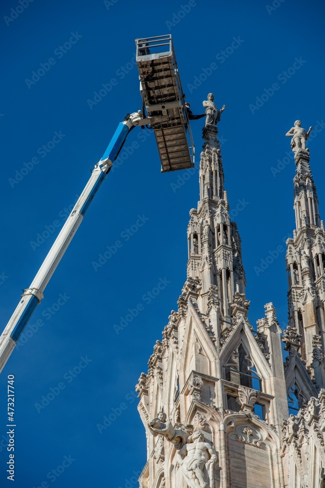 Technicians on lifting platform for scheduled maintenance plan and study of the degradation phenomena of the Milan cathedral