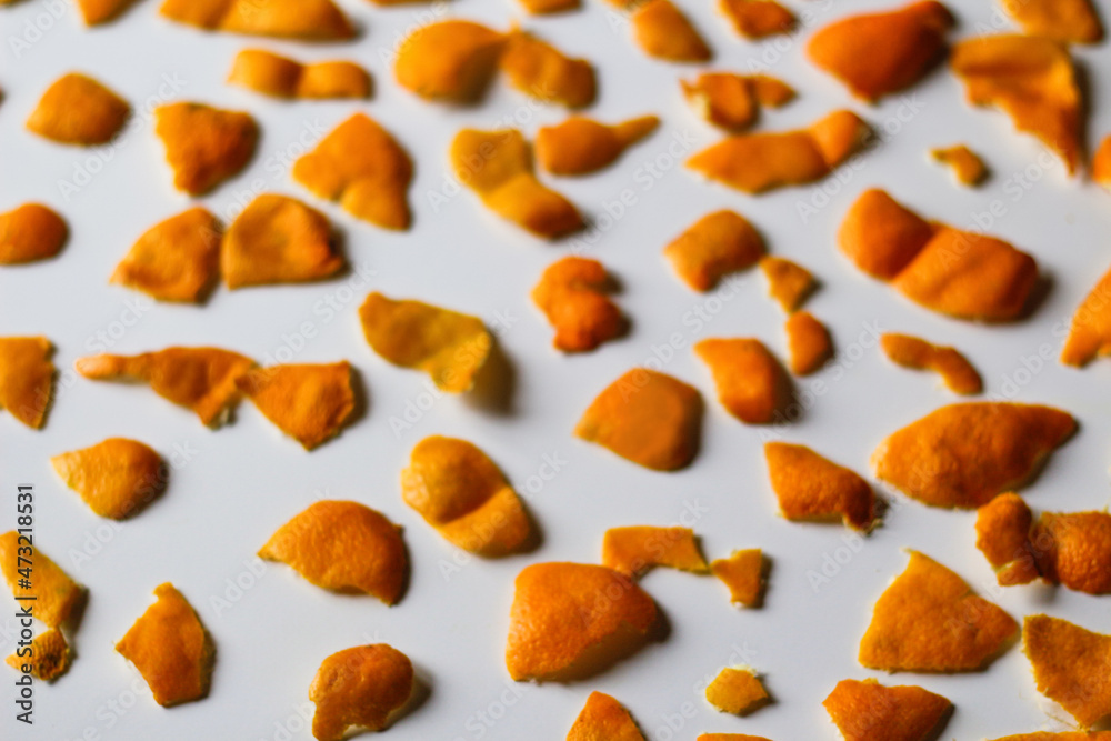 Defocus Christmas background. modern trendy peels of orange and tangerine on a white background. Many small pieces of dried peel. Pattern. Isolated. Orange bright color. Out of focus