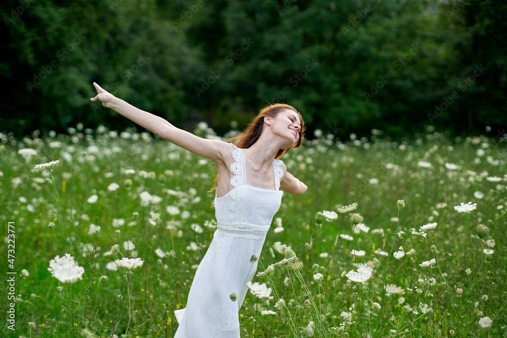 Fototapeta premium cheerful woman in a field with flowers in a white dress in nature