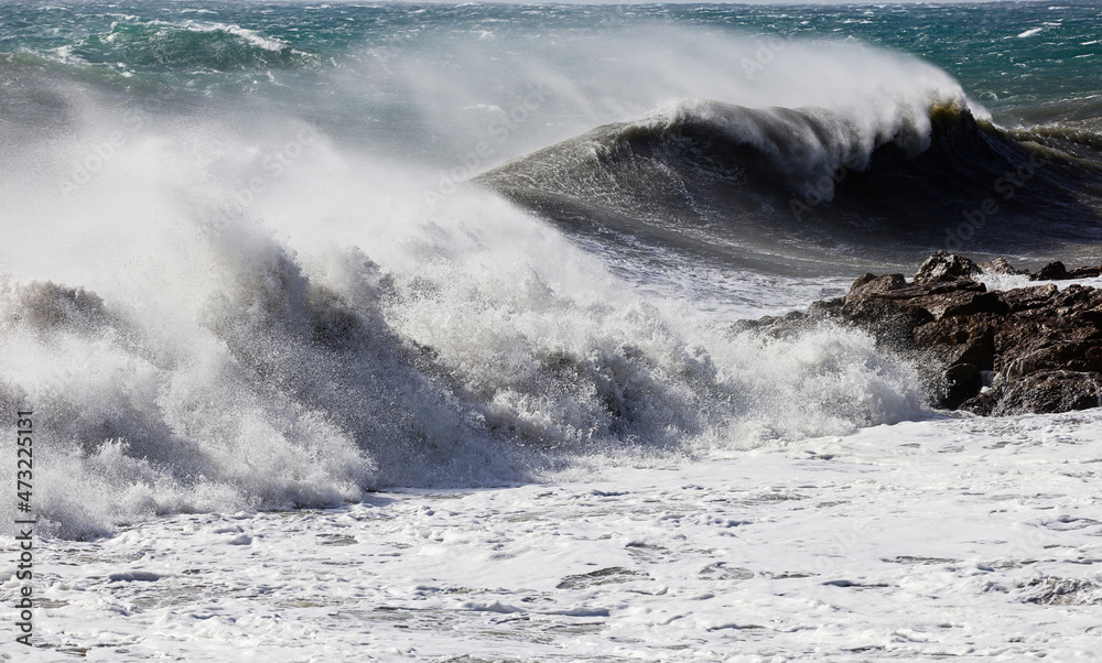 big waves breaking on the shore, with white foam