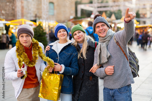 Father, mother and kids standing at christmas fair together. Father pointing finger.
