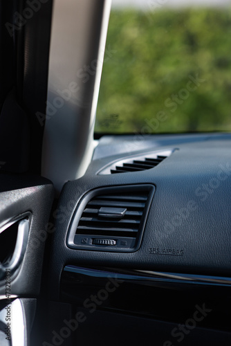Close up of plastic car air ventilation grills from air condition system in a compact Japanese car. Selective focus points. Seeing a front glass windshield showing a park in the morning.