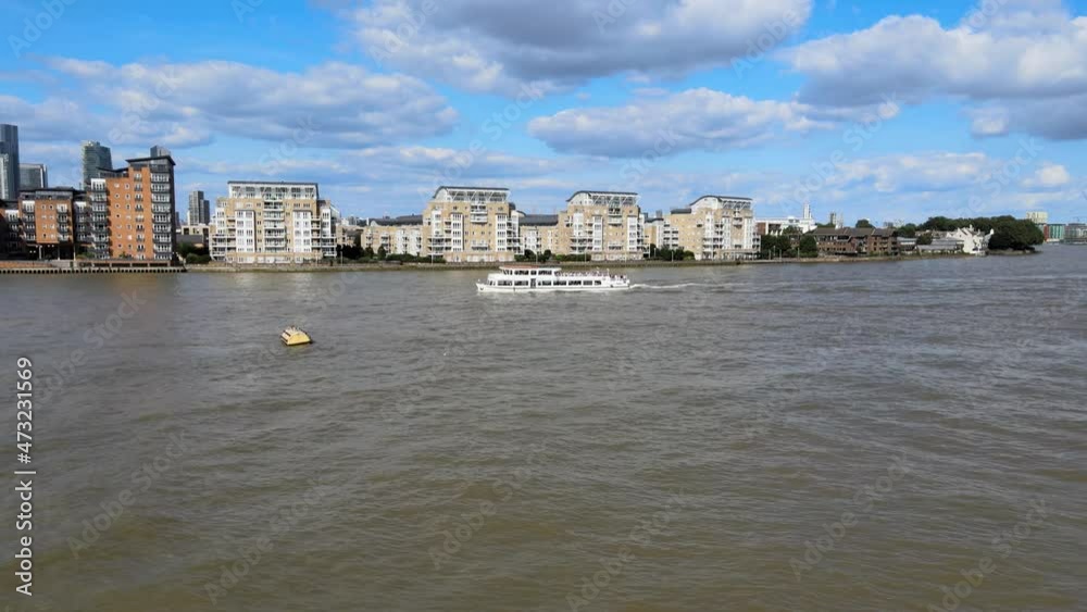 tourist sightseeing boat sailing on wide Thames river. Apartment buildings on waterfront. London, UK tourist sightseeing boat sailing on wide Thames river. Apartment buildings on waterfront. London, UK