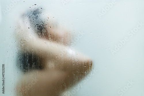 Unrecognizable Asian young woman enjoy taking a shower in the shower box in bathroom.