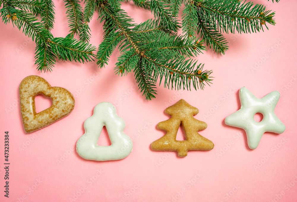 Top view of Christmas cookies on pink paper background and pine tree branch Top view of Christmas cookies on pink paper background and pine tree branch
