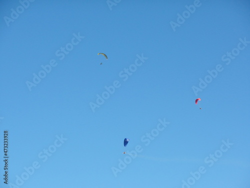 Three men parachute in the blue sky