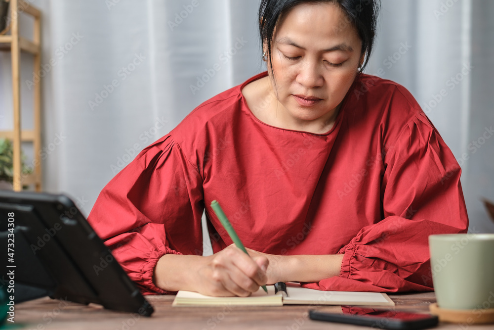 asian woman writing on notebook at working desk at home asian woman writing on notebook at working desk at home