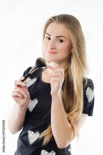 Portrait of a young beautiful girl with a makeup brush near the face. Isolated