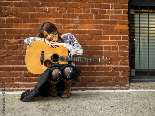 Young female Indigenous artist playing guitar outdoors photo