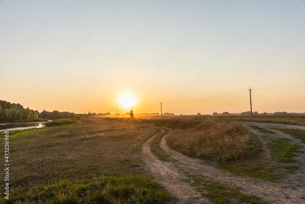Country road in golden lights of beautiful bright sunset